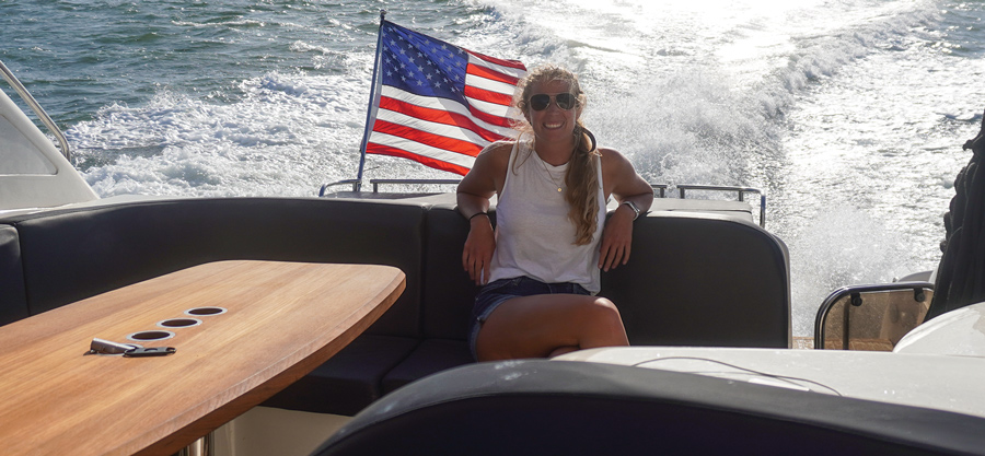 woman sitting on moving boat with an American flag behind her