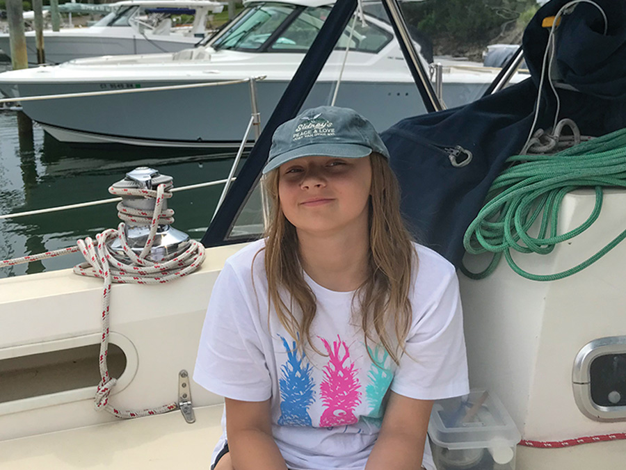 young girl sitting on boat wearing a hat